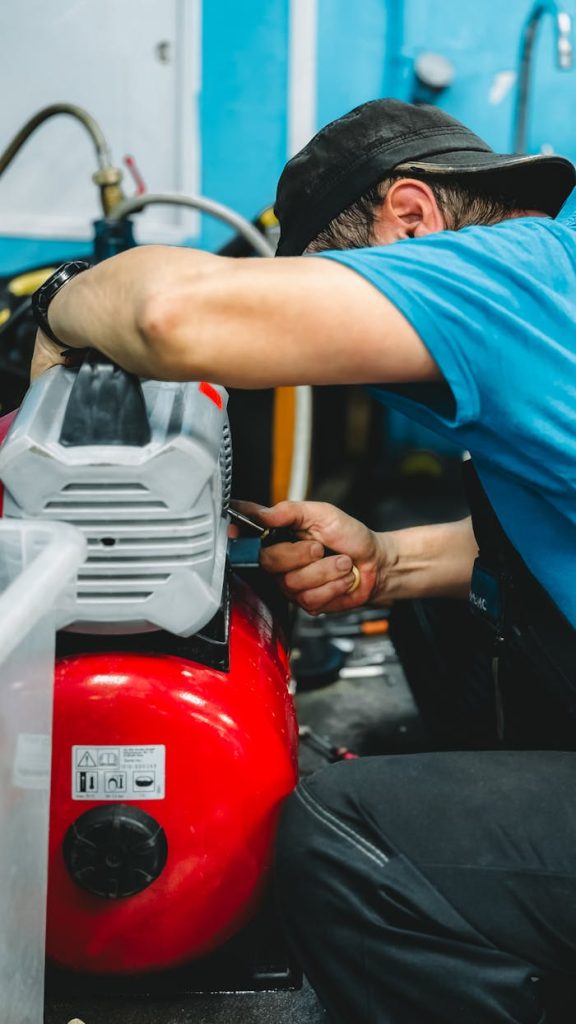 A focused technician repairing an air compressor in a workshop environment.